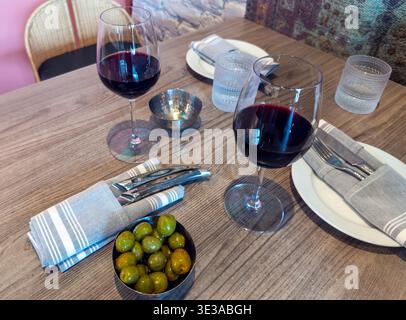Gemütliches Ambiente mit Gläsern Rotwein und einer kleinen Schüssel Oliven in einem Restaurant Stockfoto