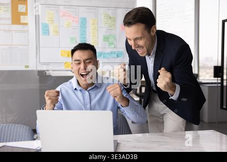 Aufgeregt verschiedene Kollegen schreien ja, hebe die Fäuste beim Blick auf das Notebook Stockfoto