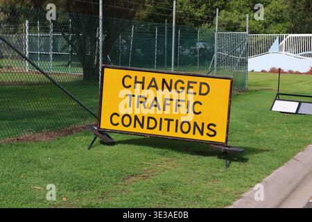 Gelbes Warnschild für geänderte Verkehrsbedingungen an einem grasbewachsenen Rand Stockfoto