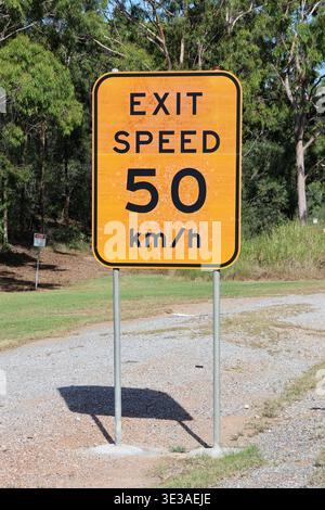Australisches Ausfahrt Geschwindigkeitsschild 50 km/h auf ländlicher Straße mit Bäumen im Hintergrund Stockfoto