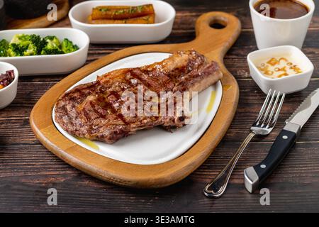 Saftiges gegrilltes Ribeye-Steak auf Holzschneidebrett Stockfoto
