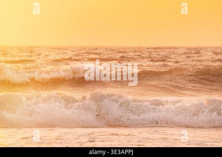 Sonnenuntergang über dem Meer. Riplpe Meerwasseroberfläche mit kleinen Wellen. Wasserschaumspritzer. Wunderschöne Naturlandschaft Stockfoto