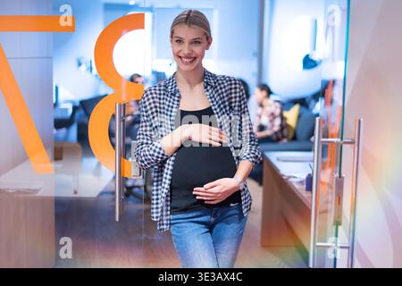 Junge schwangere Frau in ein modernes Büroumfeld. Konzept der Work-Life-Balance, weibliche Empowerment, Karriere in der Schwangerschaft und modernes Busin Stockfoto