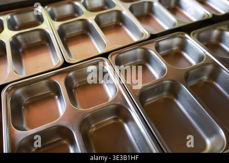Nahaufnahme eines leeren Metallfachs in der Cafeteria der Schule oder des Gefängnisses. Gefühl von institutioneller Routine und Leere vermittelt durch sh Stockfoto