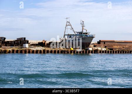 Pellestrina, Venedig, Italien - 25. Oktober 2025: Altes verwittertes Fischerboot in einer Werft entlang der Lagune von Venedig Stockfoto