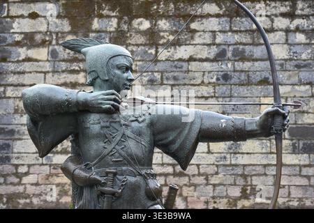 Die Robin-Hood-Statue steht stolz auf der Castle Road in Nottingham, England und richtet seinen Pfeil in Richtung des historischen Torhauses von Nottingham Castle. Stockfoto