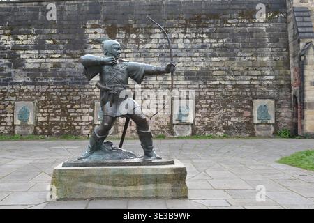 Die Robin-Hood-Statue steht stolz auf der Castle Road in Nottingham, England und richtet seinen Pfeil in Richtung des historischen Torhauses von Nottingham Castle. Stockfoto