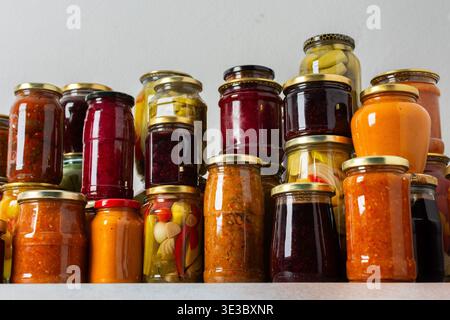 Canning ist eine häufige Aktivität in der Küche, da die Theke mit Gemüse und Obst gefüllte Gläser säumen. Diese Praxis hilft dabei, Lebensmittel für den Gewinn zu bewahren Stockfoto