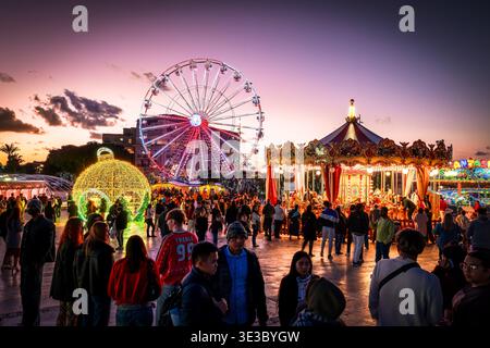 Weihnachtsmarkt in Santa's City in Valletta, Malta. Rudolph's Big Wheel und Karussell beleuchten Pjazza Tritoni unter einem leuchtend violetten TW Stockfoto
