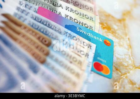 KIEW, UKRAINE - 28. JANUAR 2026 Schwedbank-Karte und schwedische Kronen-Geldscheine auf dem Tisch in Nahaufnahme. Swedbank ist die beliebteste Bank in Schweden Stockfoto