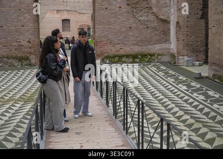 Bäder von Caracalla, Terme di Caracalla. Rom, Italien. Erhaltener römischer Mosaikboden, der von jungen Touristen gesehen wird. Stockfoto