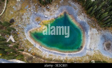 Von oben aus der Vogelperspektive auf den Karersee. Smaragdgrüne und türkisfarbene Gewässer, umgeben von felsigen Küsten und Tannenwäldern in den Dolomiten. Vertikale Aufnahme wird angezeigt Stockfoto