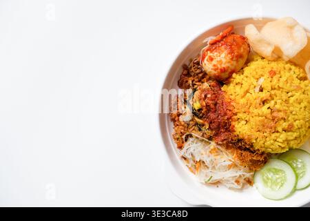 Indonesischer Kurkuma-Reis oder nasi kuning ist aromatischer Reis, der mit Kurkuma und aromatischen Gewürzen zubereitet wird und mit traditionellen Beilagen serviert wird Stockfoto