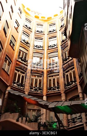Innenhof der Casa Milà (La Pedrera) mit Blick nach oben, mit kunstvollen Eisenarbeiten und bemalter Decke, Antoni Gaudí Wahrzeichen, Barcelona, Spanien. Stockfoto
