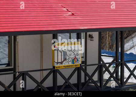 Japanisches Warnschild vor fallendem Dachschnee im Skigebiet Hakuba Cortina in Nagano Stockfoto