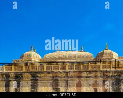 Jaipur, Indien, 19.02.2020. Ein Niedrigwinkelfoto mit den bunten gestreiften Kuppeln und den komplizierten Steingeländern des historischen Amer Fort unter einem Vigleie Stockfoto