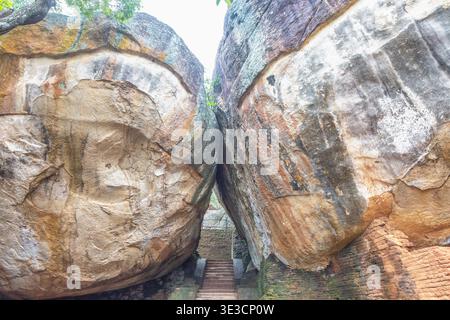 Sigiriya alte Felsenfestung in Sri Lanka. Alte Treppe zwischen massiven verwitterten Felsblöcken, die nach oben führen, der Grand Archway der Natur zum Historischen Stockfoto