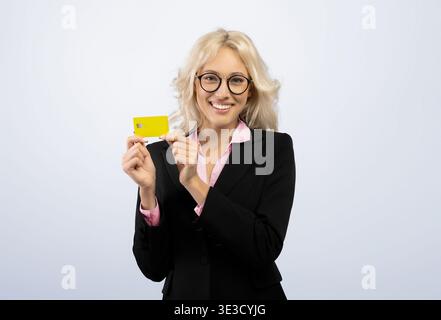 Geschäftsfrau hält die gelbe Karte mit einer Hand und lächelt in einer einfachen Umgebung weit an der Kamera Stockfoto