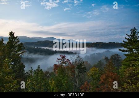 Blick vom Boyd Gap Overlook mit Baumkronen, Nebelschichten bewaldeten Hügeln, fernen Bergen und einem blauen Himmel mit hohen Wolken in East Tennessee. Stockfoto