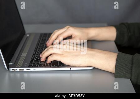 Person, die auf einem Laptop am Schreibtisch für Fernarbeit und Produktivität tippt Stockfoto