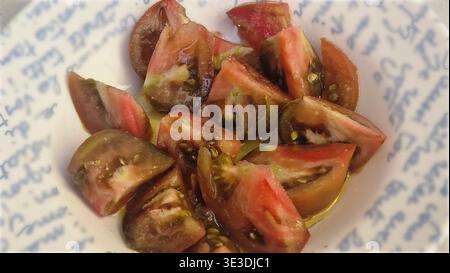Frisch geschnittene Tomatenstücke in einer weißen Schüssel mit Olivenöl Stockfoto