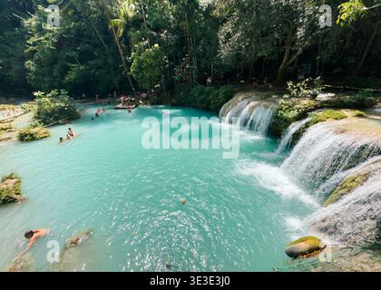 Cambugahay Falls in Siquijor, Philippinen, mit türkisfarbenen Pools, kaskadierenden Wasserfällen und Besuchern, die in einem tropischen Wald schwimmen. Stockfoto