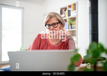 Ältere Frau, die während des Ruhestands im Home Office an einem Laptop arbeitet. Stockfoto