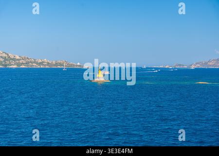 Gelbe Navigationsboje, die auf tiefblauem Meer schwimmt. Minimaler Meereshintergrund und Navigationskonzept Stockfoto