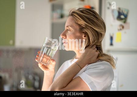 Glückliche entspannte Frau genießt das Trinken von erfrischendem Wasser aus Glas am frühen Morgen, gesunde Gewohnheit. Stockfoto