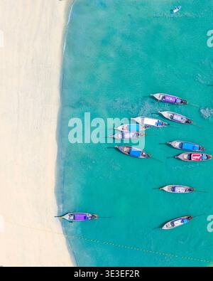 Railay West Beach, Krabi, Thailand – 23. Februar 2020: Longtail-Boote liegen in seichten Gewässern neben der Sandküste, von oben gesehen. Stockfoto