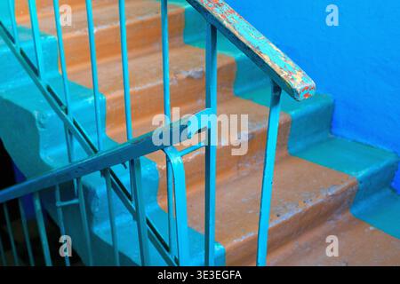 Treppe eines alten Wohngebäudes mit abgenutzten Betontreppen und türkisfarbenen Metallgeländern. Hochwinkelansicht, die den authentischen Vintage in zeigt Stockfoto