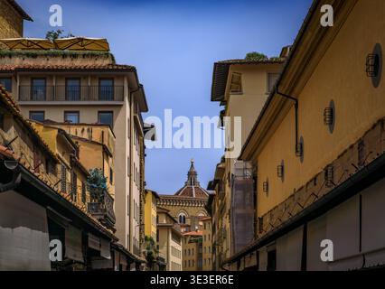 Die mittelalterlichen Steinbauten der Ponte Vecchio in Florenz, Italien, mit verwitterten gelben Fassaden, blumengefüllten Balkonen und rustikalen Ziegeldächern Stockfoto