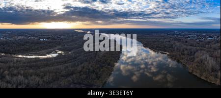 Aus der Vogelperspektive zeigt die Weichsel in der Nähe von Warschau, Polen, die sich bei Sonnenuntergang durch baumlose Wälder und Vororte schlängelt, mit gebrochenen Wolken, die sich auf der spiegeln Stockfoto