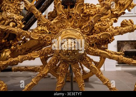 München, Deutschland - 29. März 24: Nahaufnahme eines aufwändig geschnitzten und vergoldeten Holzrads aus einer historischen königlichen Kutsche auf Schloss Nymphenburg in München Stockfoto