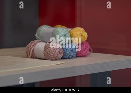 Bunte Garnbällchen auf dem Tisch mit Stricknadeln in weichem Licht. Bastel- und Hobbykonzept mit Materialien zum Stricken und Häkeln. Geeignet Stockfoto