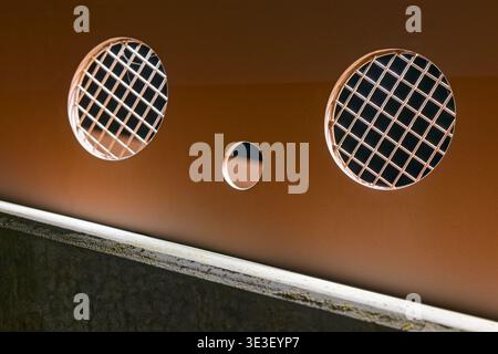 Metalltafel mit zwei runden Lüftungsgittern mit Gittermuster und einem kleinen runden Loch in der Mitte, beleuchtet durch sanfte Beleuchtung. Stockfoto