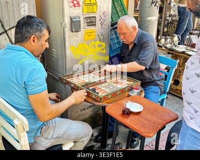 ISTANBUL, TÜRKEI - 11. JULI 2022: Zwei nicht identifizierte Männer in Istanbul, Türkei sitzen an einem Tisch in einem Straßencafé, während sie Backgammon spielen. Stockfoto