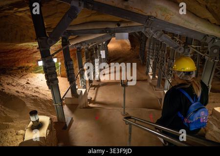 Besucher mit Schutzhelm steigen in die Sandsteintunnel der Schlossberghöhlen in Homburg, Saarland, ab. Stockfoto