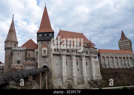 Außenansicht der Burg Corvin mit Holzbrücke, Steintürmen und Restaurierungsgerüsten in Hunedoara, Transsilvanien, Rumänien. Stockfoto