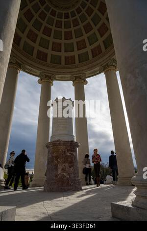 München, Deutschland - 29. März 24: Besucher stehen zwischen den Steinsäulen im Monopteros-Pavillon im Englischen Garten Münchens, mit Sonnenlicht und shado Stockfoto