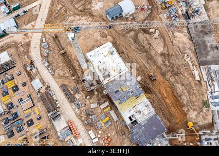 Viel befahrene Baustelle mit Kran, Ausrüstung und Baumaterialien. Draufsicht aus der Luft. Stockfoto