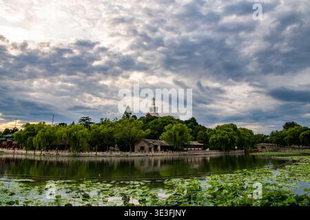 Dramatische Wolkenformationen über dem Beihai Park vor Sonnenuntergang, mit Reflexionen auf dem See in Peking, China. Sommerabendstimmung. Stockfoto