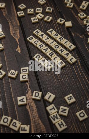 Lviv Ukraine 02.26.26 Fliesen beschriften den Nationalfeiertag im April auf einer hölzernen Oberfläche. Wörter sind verstreut und einige Buchstaben liegen in der Nähe. Stockfoto