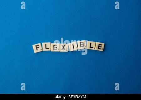 Lviv Ukraine 02.26.26 am Nationalen Scrabble-Tag wird das Wort flexibel mit Buchstabensteinen auf blauer Oberfläche gebildet, die Spieler zum Spielen einladen und Stockfoto