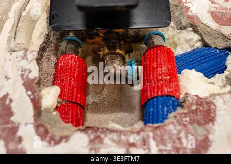 Beschädigte Rohrleitungen mit freiliegenden Rohren und ein Wasserleck in der Wand der Duschkabine Stockfoto