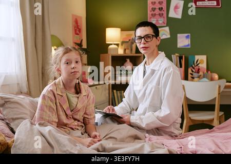 Ärztin berät Kranke Kind Mädchen Patientin sitzend auf Bett Stockfoto