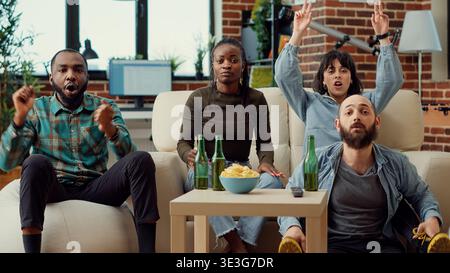 Eine multiethnische Gruppe von Fußballfans, die ein Fußballspiel sehen, Bier trinken, sich anfeuern, um ein Tor zu schießen und die Meisterschaft zu gewinnen. Menschen, die Sportwettkämpfe im Fernsehen genießen. Stativaufnahme. Stockfoto