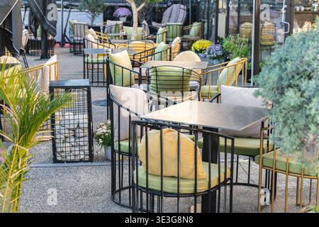 Terrasse im Freien mit modernen Möbeln, Tischen und Stühlen. Charmantes Street Cafe mit gemütlichem Patio-Sitzplatz in lebhafter urbaner Umgebung. Sommerpause im Freien Stockfoto