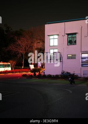 Wuhan, China - 21. März 2025: Außenansicht eines rosafarbenen Wohngebäudes mit mehreren Klimaanlagen. Die Abbildung zeigt einen Bus im Hintergrund A Stockfoto