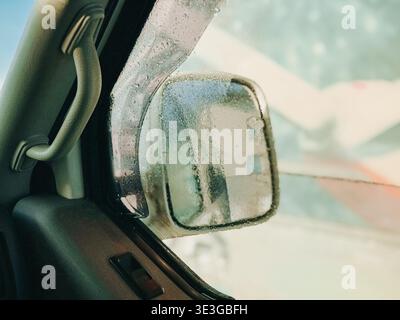 Nahaufnahme eines mit Kondenswasser bedeckten Seitenspiegels aus dem Fahrzeuginneren. Atmosphärisches Bild zur Hervorhebung von kaltem Wetter, reduzierte Sichtbarkeit Stockfoto